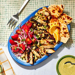 Platter of chicken on white tablecloth.