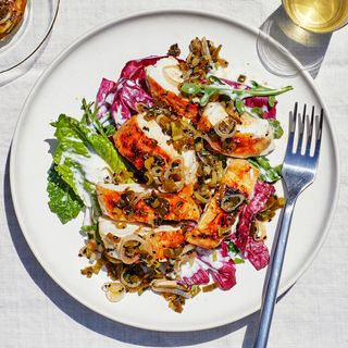 Grilled chicken breasts on a plate sliced and topped with a charred scallion relish.