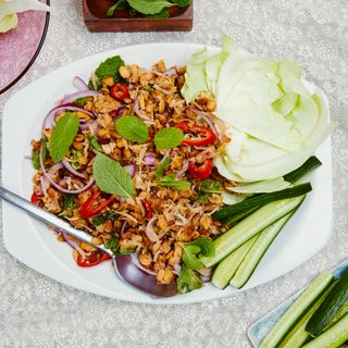 Spicy Tempeh and Coconut Larb on a white platter placed on a fabric surface.