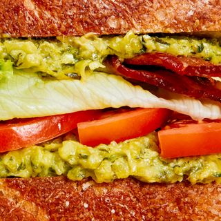 A macro view of bacon lettuce and tomato sandwiched between generous spreads of zucchini butter and bread.