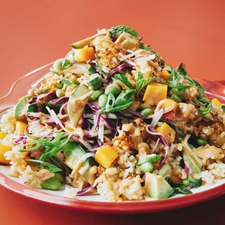 A pile of crispy rice diced mango shredded purple cabbage julienned radishes sliced Persian cucumbers sliced avocado...
